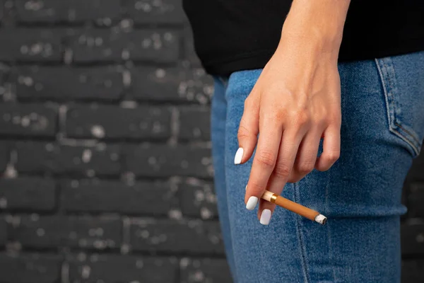 Weibliche Hand hält angezündete Zigarette aus nächster Nähe Stockbild