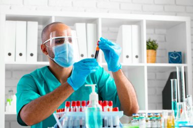 Afrikalı Amerikalı doktor veya laboratuvar çalışanı klinikte kan örneğini inceler.