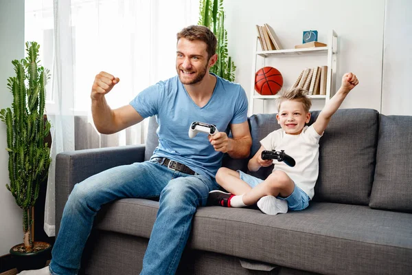 Padre y su pequeño hijo jugando videojuegos juntos en casa — Foto de Stock