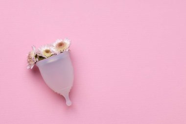 Pembe arka planda çiçekli regl bardağı