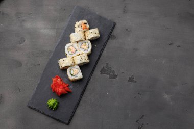 Suşi rulosunun üst görüntüsü koyu gri arkaplanda susam