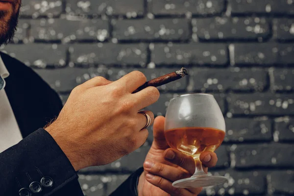 Hombre sosteniendo un vaso de whisky y cigarrillo encendido en las manos de cerca — Foto de Stock