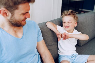 Oğlu babasıyla kanepede otururken baş parmağını kaldırıyor.