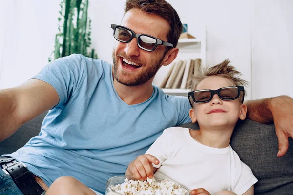 Pai e filho assistindo filmes em casa em óculos 3d e comer pipocas — Fotografia de Stock