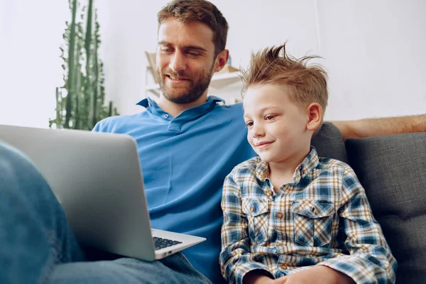아버지 와아들이 소파에 앉아서 노트북으로 무엇인가를 보고 있는 모습 — 스톡 사진