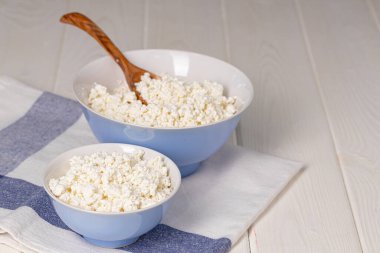 Ahşap masada bir kase süzme peynir.