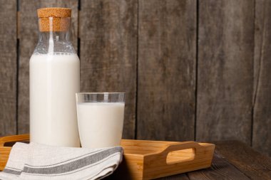 Şişe ve bir bardak süt ahşap masada.