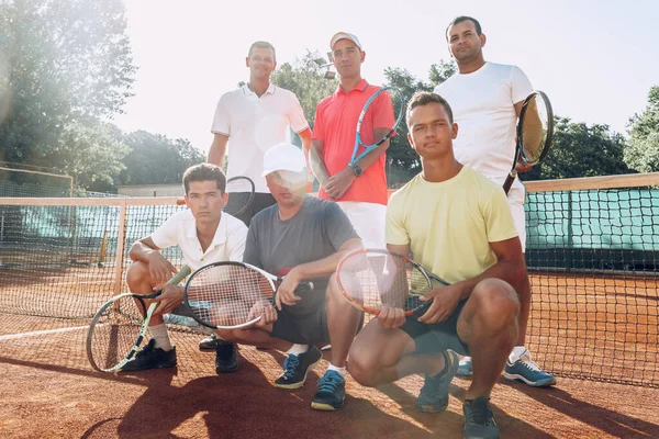 Group of six male tennis players standing on court