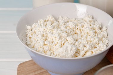 Ahşap masada bir kase süzme peynir.