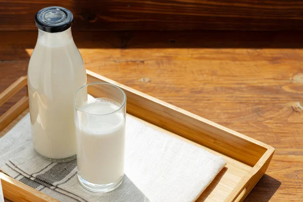 木製のテーブルの上に牛乳のボトルとガラス — ストック写真
