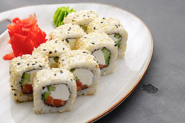 Rollo de sushi con salmón, queso filipino y sésamo en el plato de cerca — Foto de Stock