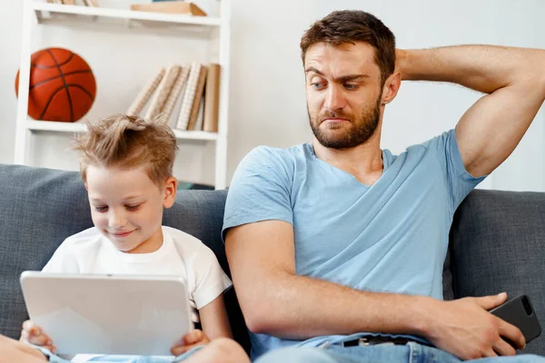 Padre preocupado mirando lo que su hijo está viendo en la tableta digital — Foto de Stock