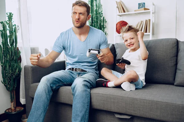 Padre y su pequeño hijo jugando videojuegos juntos en casa — Foto de Stock