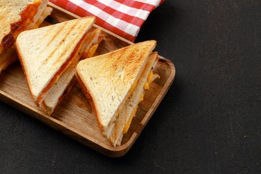Tahta kesme tahtasında peçeteyle ikiye bölünmüş sandviçler.