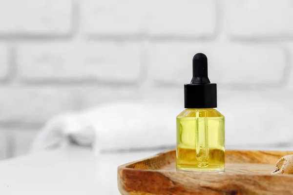 Botella de aceite cosmético amarillo en bandeja de madera de cerca — Foto de Stock