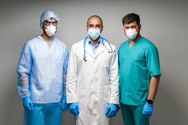 Mężczyzna lekarze w medycznym mundurze noszenie maski stojące na szarym tle — Zdjęcie stockowe