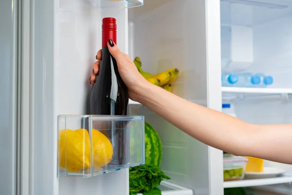 Vrouwelijke hand neemt fles wijn uit een koelkast — Stockfoto