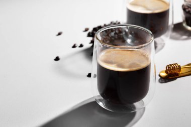 Beyaz masada bir bardak kahve ve kahve çekirdeği.