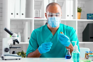 Afro-Amerikalı doktor masada oturuyor ve bir ilaç enjekte etmeye hazırlanıyor.