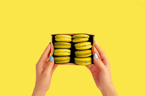 Femei mâini ține cutie cu iluminatcookie-uri macaroon galben . — Fotografie, imagine de stoc