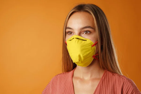 Молодая красивая случайная женщина носит защитную медицинскую маску светящегося желтого цвета — стоковое фото