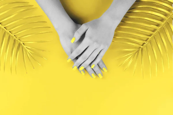 Женские руки с маникюром светящегося желтого цвета на том же фоне — стоковое фото