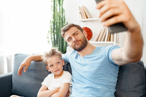 아버지 와아들이 소파에 앉아 스마트폰으로 비디오 통화를 하고 있는 모습 — 스톡 사진