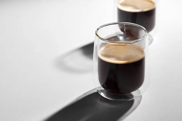 Americano café dans des tasses en verre sur fond blanc avec de longues ombres — Photo