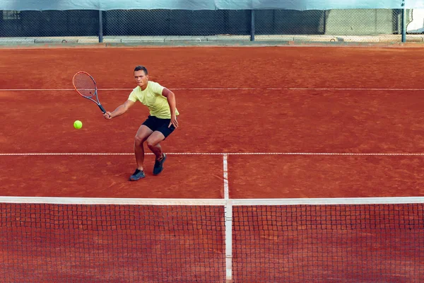 Jeune homme beau jouant au tennis sur le court de tennis — Photo