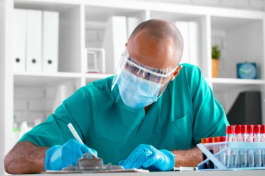 Afro-Amerikan doktor masasında otururken not alıyor.