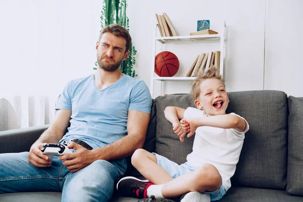 Padre y su pequeño hijo jugando videojuegos juntos en casa — Foto de Stock