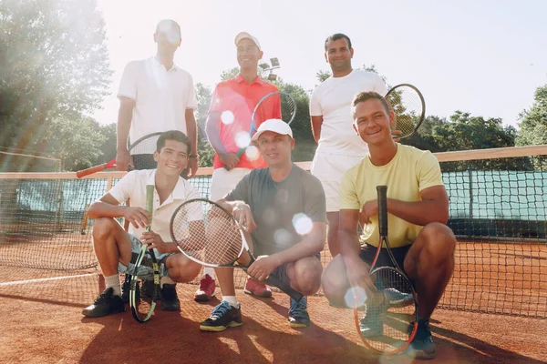 Group of six male tennis players standing on court