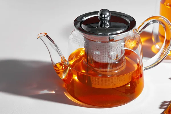 Стеклянный чайник с фруктовым чаем на фоне стола — стоковое фото