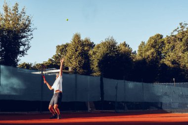 Genç proffesional tenis oyuncusu servis yapıyor.