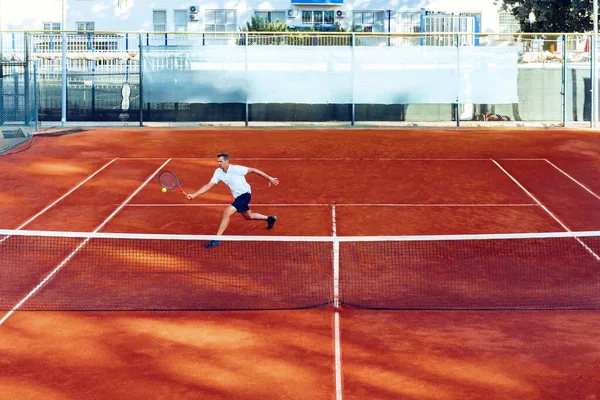 Adam uzaktan, kil tenis sahasında tenis oynuyor. — Stok fotoğraf