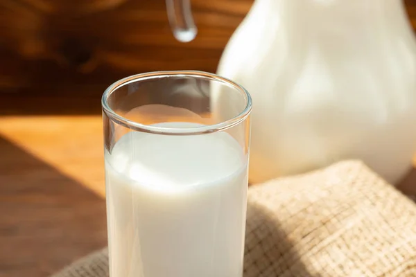Стеклянный кувшин молока на деревянном столе — стоковое фото