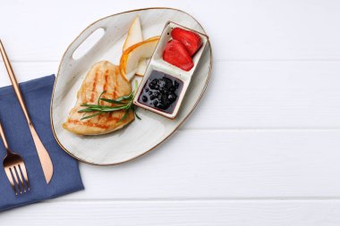 Kızarmış tavuk göğsü ve beyaz ahşap masada çilek sosu.