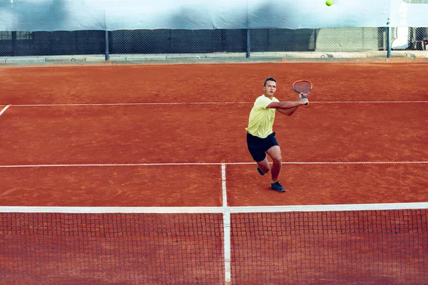 Jeune homme beau jouant au tennis sur le court de tennis — Photo