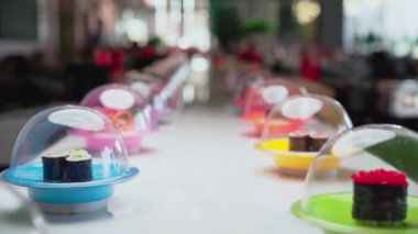 Japon restoranında renkli tabaklar içinde suşi hazırlanmış konveyör bandı treni.