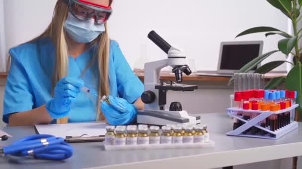 Une travailleuse de laboratoire remplit la seringue avec un médicament expérimental contenu dans un flacon — Video