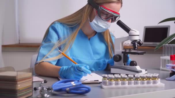 Vrouw laboratoriummedewerker neemt notities over bloedmonsters — Stockvideo