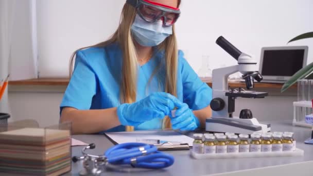 Une travailleuse de laboratoire remplit la seringue avec un médicament expérimental contenu dans un flacon — Video