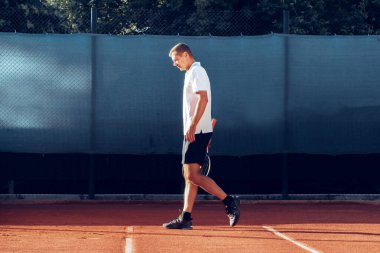 Tenis oyuncusu tenis kortunda raketle ayakta duruyor
