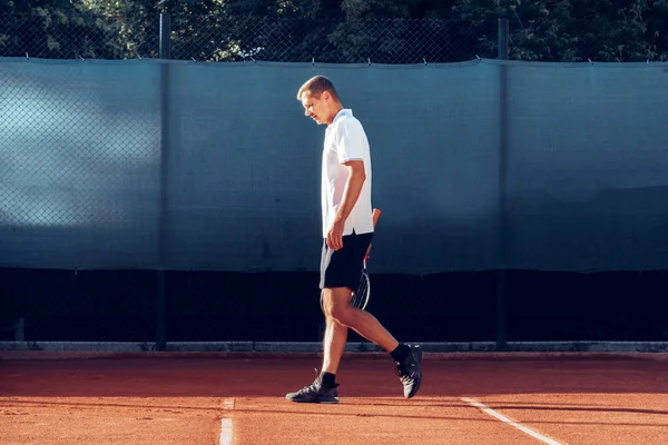 Tenis oyuncusu tenis kortunda raketle ayakta duruyor