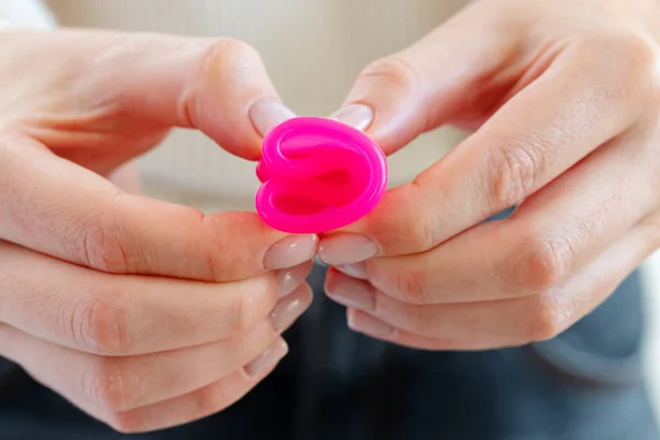 Frau im weißen Pullover mit rosa Menstruationstasse in der Hand aus nächster Nähe — Stockfoto