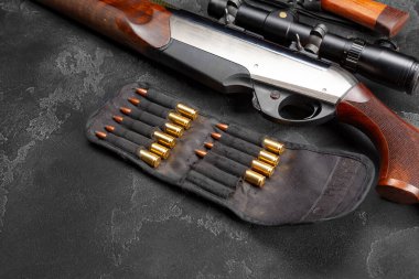 Avcı tüfeğine ve koyu gri arka plandaki fişeklere yakın dur.