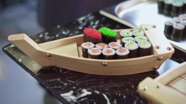 Şef, suşi rulolarını ahşap tekne tabağına koyar.