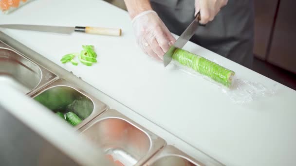 Manos de un chef cocinando rollo de sushi de aguacate en una cocina de restaurante — Vídeo de stock