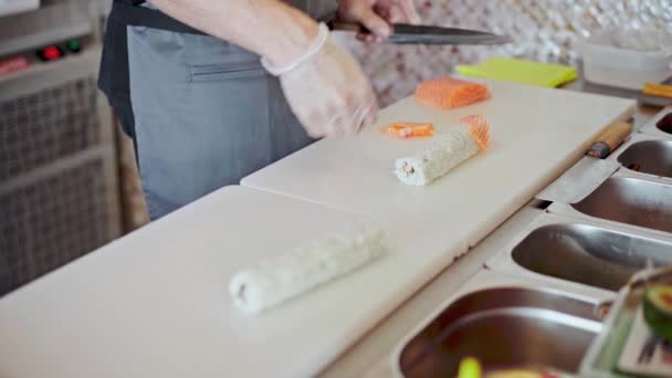 Mannelijke handen in handschoenen koken sushi rollen in een restaurant keuken close-up — Stockvideo