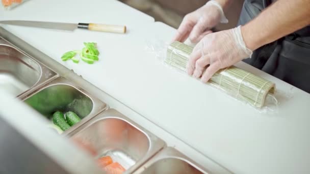 Mężczyzna ręce w rękawiczki gotowanie sushi rolki w a restauracja kuchnia zbliżenie — Wideo stockowe